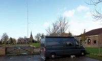 Op de camperplaats in IJlst. Achter het hek onze mast met VHF-vertical en 40m-dipool draadantenne.