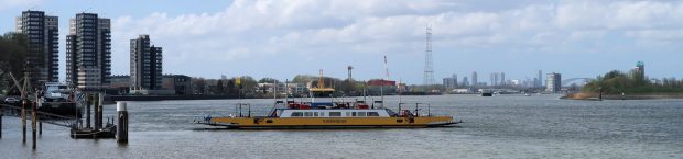 De veerboot bij de molens van Kinderdijk. Op de achtergrond de stad Rotterdam.