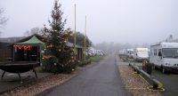 Klaar voor vanavond: kerstboom, grote vuurkorf en op de achtergrond het blokhut-caffeetje van de camperplaats. Wij staan een eindje verder, links van de weg.