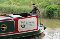 Deze huurder stuurt zijn narrowboat behoedzaam de sluis in.