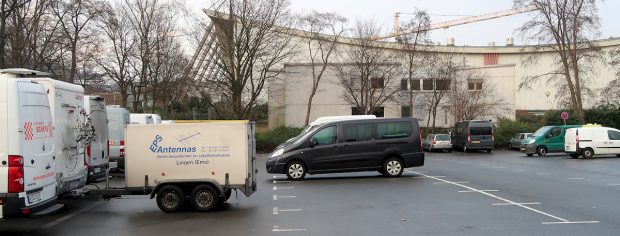 Handelaren op een rij, wachten tot ze naar binnen mogen om op te bouwen. Wij staan rechts achteraan, tegen die groenstrook.