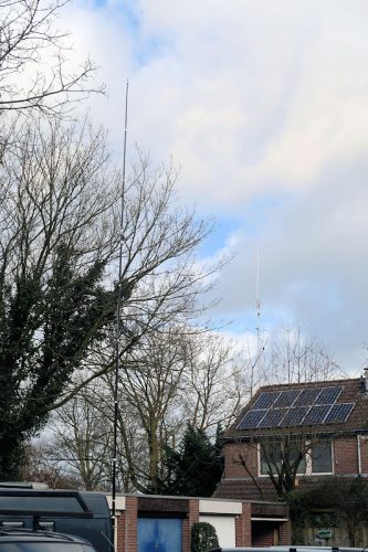 De dualbandantenne met op de achtergrond de antennes aan ons huis.