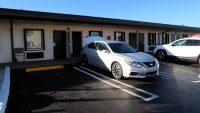 Een motel: kamer op de begane grond, de auto ervoor geparkeerd.